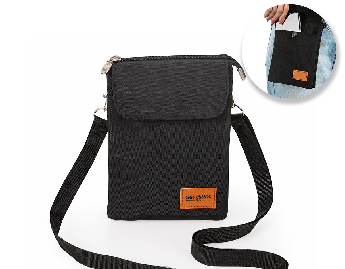 Mini bolsa transversal de nylon com plaquinha frontal em couro sintético personalizável. Possui tecido impermeável, bolso frontal com botão de fechamento imantado, bolso traseiro de zíper e bolso superior de zíper com duas divisórias internas e espaço para celular. Acompanha alça ajustável de uso transversal (removível).