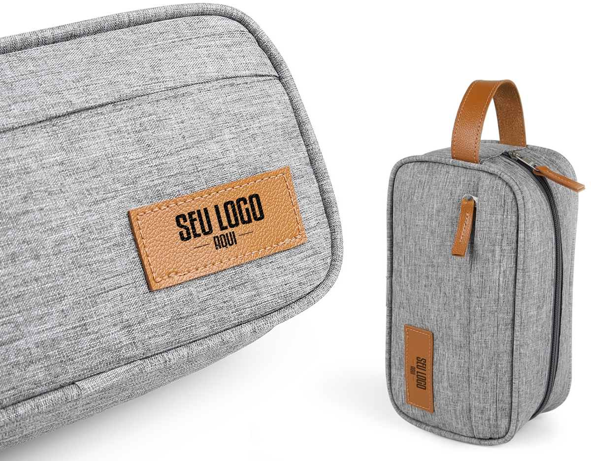 Necessaire confeccionada em poliéster com detalhes em couro sintético, possui dois compartimentos com zíper, alça para transporte e alça pequena para acesso de chaveiro ou gancho.