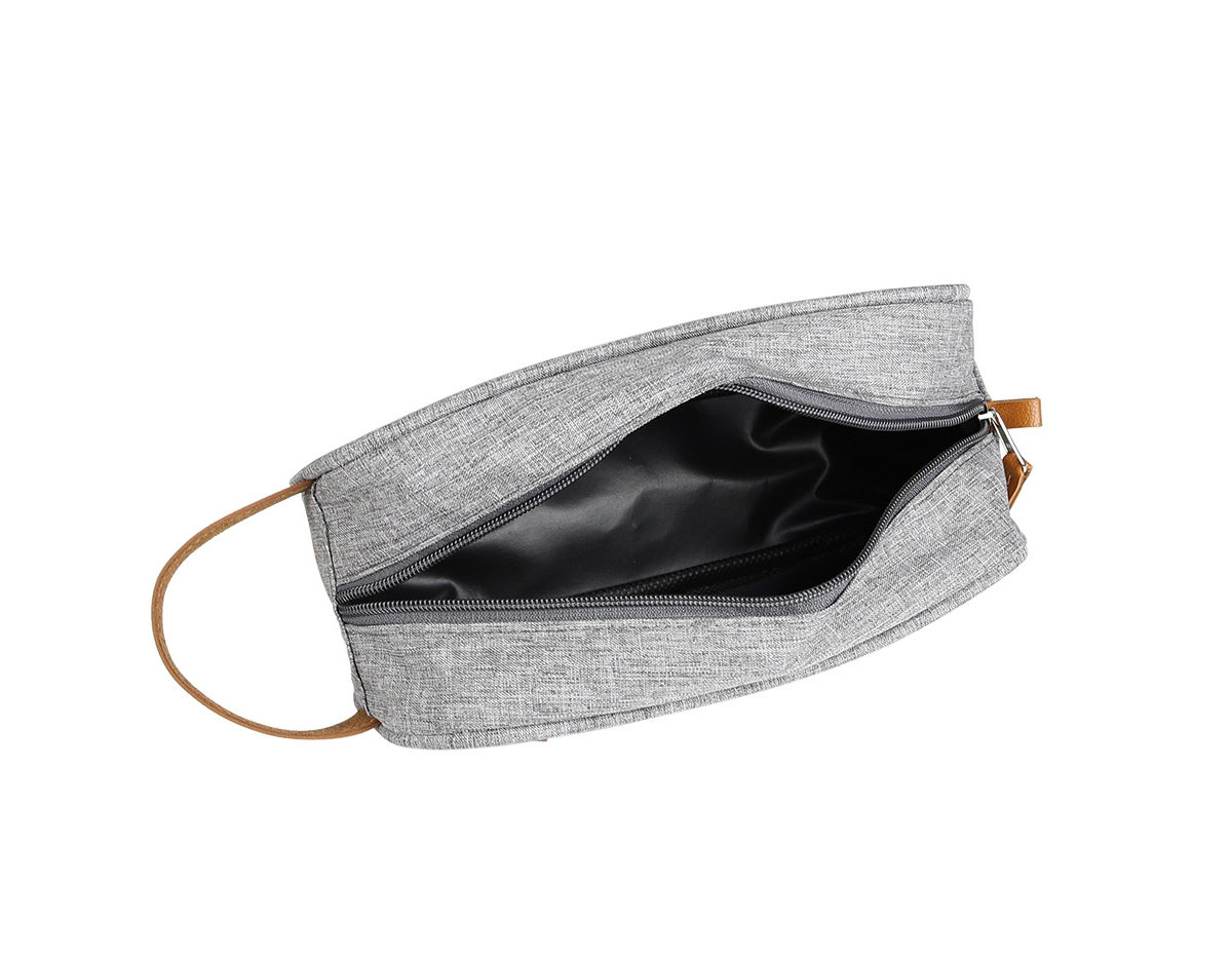 Necessaire confeccionada em poliéster com detalhes em couro sintético, possui dois compartimentos com zíper, alça para transporte e alça pequena para acesso de chaveiro ou gancho.